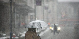 Mann mit einem Schirm im Winterwetter oder Schnee