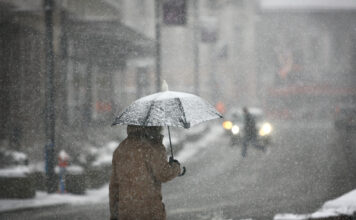 Mann mit einem Schirm im Winterwetter oder Schnee