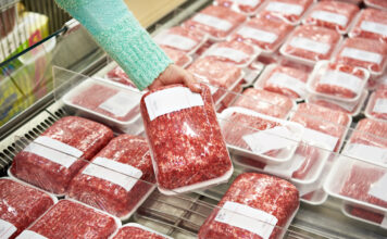 Käufer-Frau wählt gehacktes Fleisch im Supermarkt