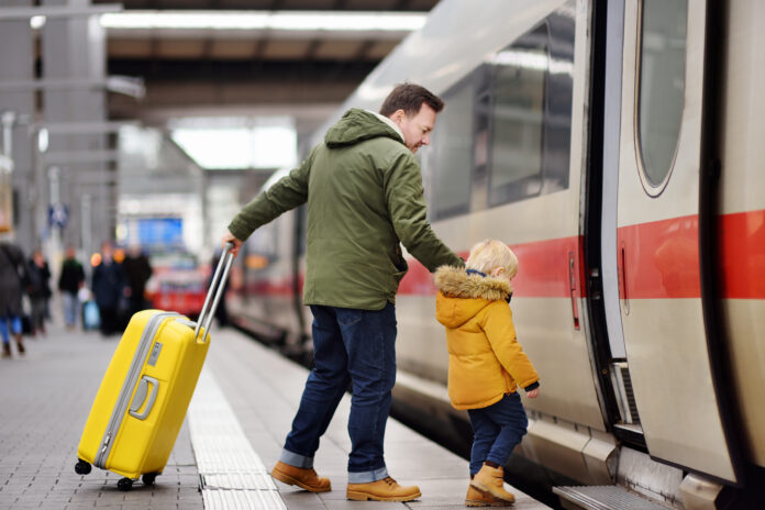 Ein Vater steigt mit seinem Sohn in einen Zug.