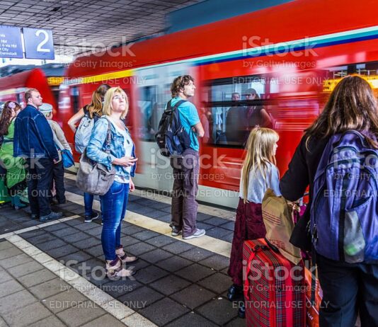 EInige Fahrgäste, sowohl Erwachsene als auch Kinder, steigen in einen Zug der Deutschen Bahn. Sie haben Gepäck dabei und stehen vor den Zugtüren, weil sie darauf warten, dass die Türen geöffnet werden und sie losfahren können