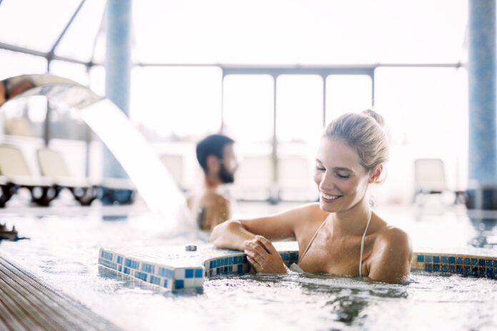 Eine Frau entspannt sich im Pool und genießt ihre Auszeit.