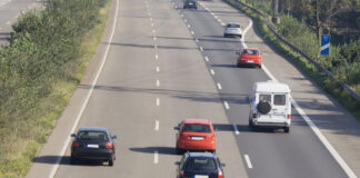 Verschiedene Autos fahren auf einer deutschen dreispurigen Autobahn mit mittlerer Grünfläche