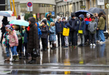 Eine Gruppe von Schülern auf der Straße mit Schirmen