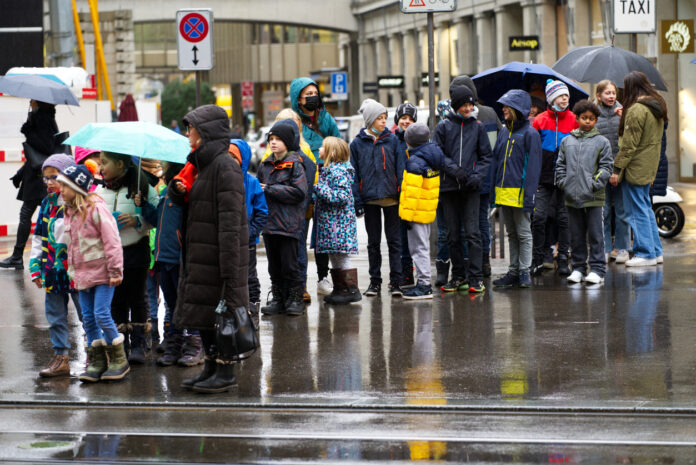 Eine Gruppe von Schülern auf der Straße mit Schirmen