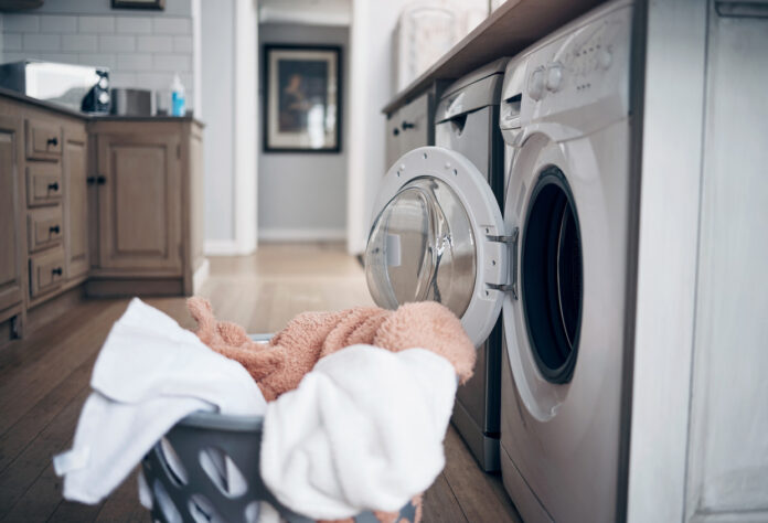 Ein Korb mit Wäsche steht vor einer Waschmaschine