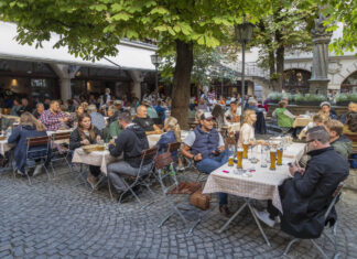 Gäste und Touristen sitzen in einem Biergarten im Freien