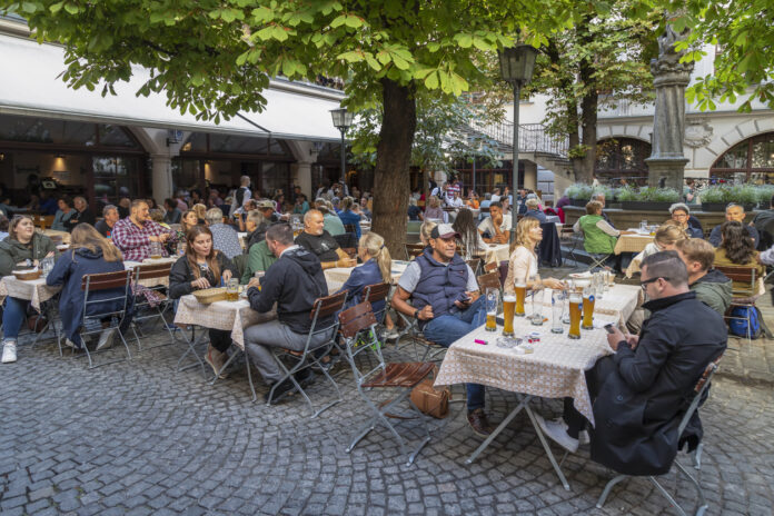 Gäste und Touristen sitzen in einem Biergarten im Freien