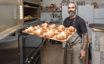 Einen Wecker steht mit einem Tablett und Broten in einer Bäckerei