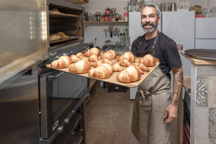 Einen Wecker steht mit einem Tablett und Broten in einer Bäckerei