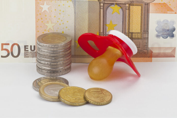 Ein Schnuller liegt neben Hartgeld und einem 50-Euro-Schein