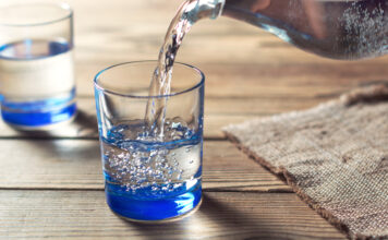 Wasser wird aus einer Karaffe in ein Glas gegossen.