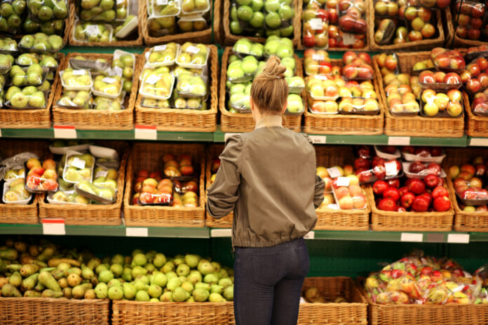 Frau steht an der Obst- und Gemüsetheke im Supermarkt.