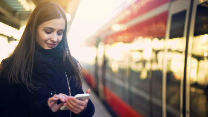 Frau kauft Ticket über Handy für Zugfahrt