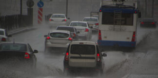 Autos fahren auf einer überfluteten Straße.