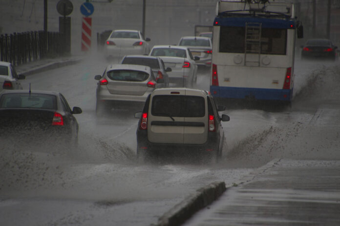 Autos fahren auf einer überfluteten Straße.