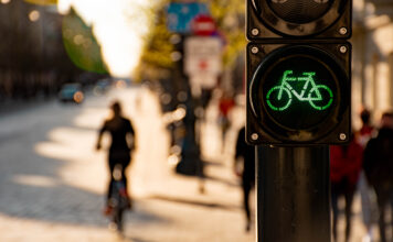 Eine Ampel an einer Fahrradstraße und ein Fahrradfahrer im Hintergrund
