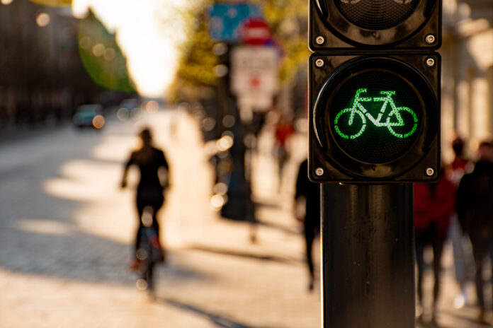 Eine Ampel an einer Fahrradstraße und ein Fahrradfahrer im Hintergrund