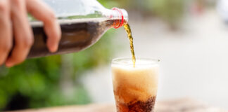 Cola wird aus einer Flasche in ein Glas gegossen.