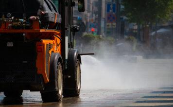 Eine Kehrmaschine führt eine nasse Straßenreinigung in der Stadt durch