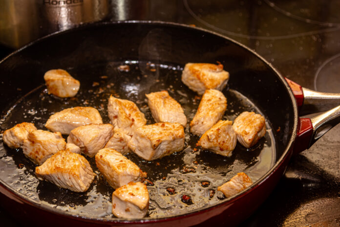 Putenfilet-Stücke werden in der Pfanne angebraten.