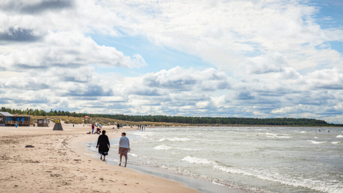 Menschen laufen am Meer am Strand entlang