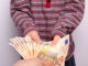Ein Kind hält 50 Euro Scheine in der Hand.