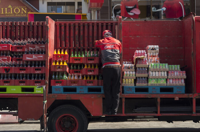 Ein Mitarbeiter von Coca Cola verläd die Getränkekisten
