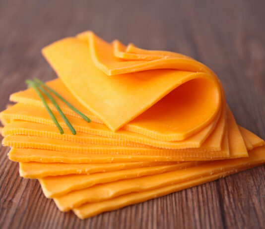 Neun Scheiben gelber Käse aufeinander gestapelt auf einer Tischplatte.