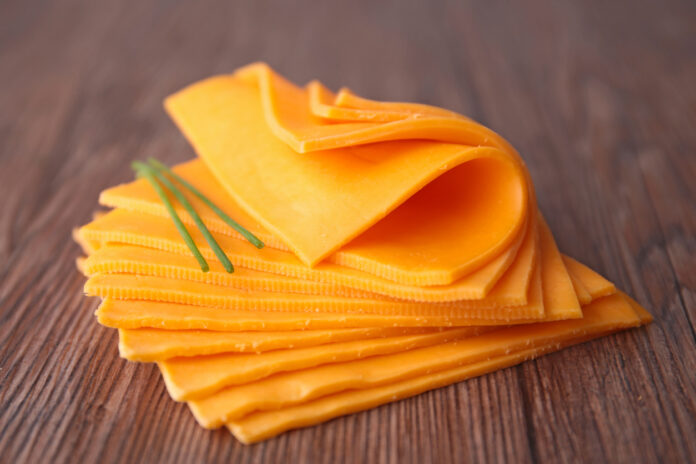 Neun Scheiben gelber Käse aufeinander gestapelt auf einer Tischplatte.