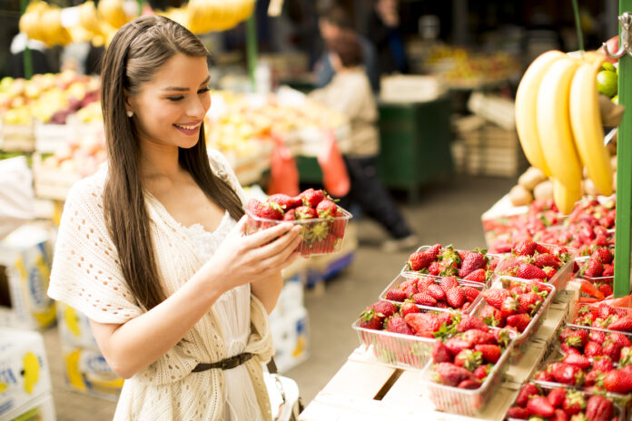 Eine Frau hält eine Schale mit Erdbeeren in der Hand.