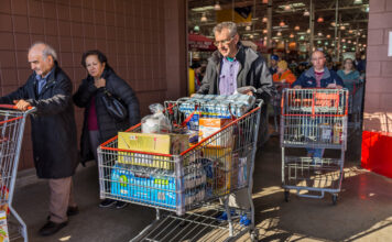Kunden verlassen einen Supermarkt mit Einkaufswagen.