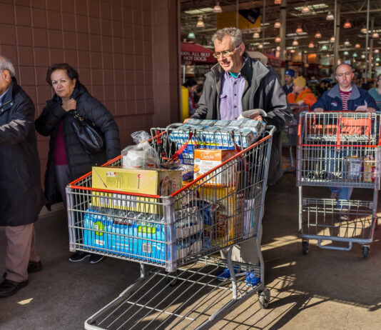 Kunden verlassen einen Supermarkt mit Einkaufswagen.