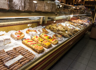 Verkaufsbereich einer Bäckerei, In der Auslage gibt es zahlreiche süße Gebäcke und Kuchen, die sauber und ordentlich aufgereiht sind. Ein Traditions-Café muss bald schließen.