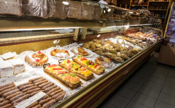 Verkaufsbereich einer Bäckerei, In der Auslage gibt es zahlreiche süße Gebäcke und Kuchen, die sauber und ordentlich aufgereiht sind. Ein Traditions-Café muss bald schließen.