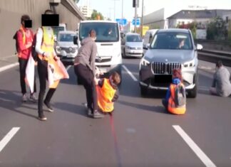 Klima-Aktivisten blockieren eine Autobahn. Die Aktivisten haben auf der Straße Platz genommen und sich auf dem Asphalt festgeklebt, um keine Autos mehr durchzulassen.
