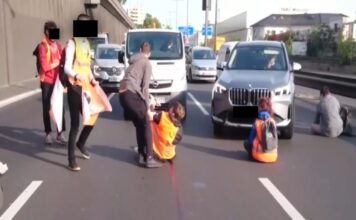 Klima-Aktivisten blockieren eine Autobahn. Die Aktivisten haben auf der Straße Platz genommen und sich auf dem Asphalt festgeklebt, um keine Autos mehr durchzulassen.