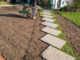 Entfernung von altem Rasen um einen neuen Trittsteinsteg in Vorbereitung für die Installation eines neuen Rasens zu legen.