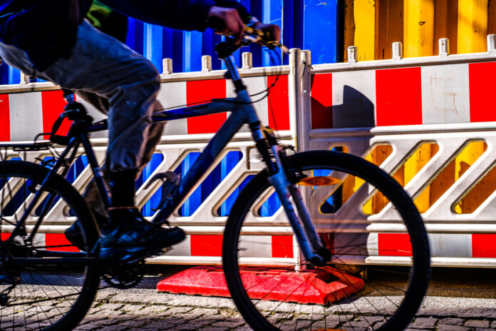 Die Seitenansicht eines Fahrradfahrers vor einer Baustelle