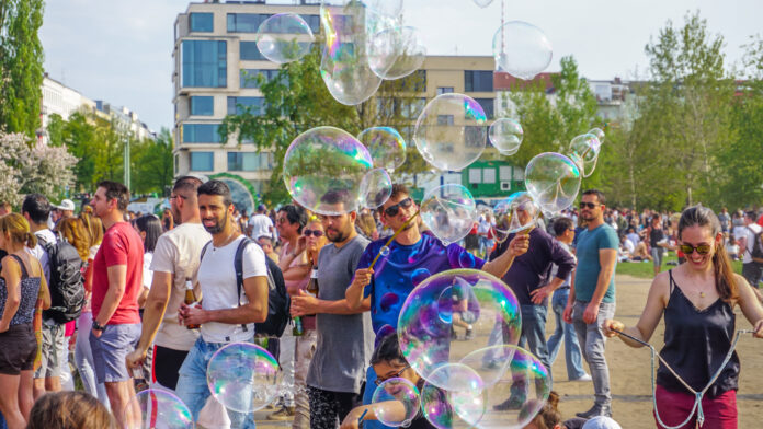 Ausgelassene Stimmung und junge Menschen mit Seifenblasen im Sommer in der Stadt bei einem Fest