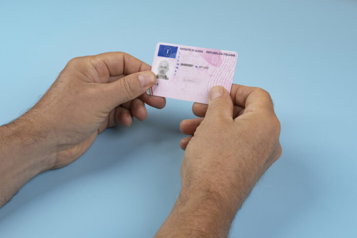 Ein Mann hält seinen Führerschein in der Hand.