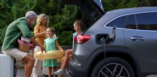 Familie mit kleinen Kindern, die Auto beladen und auf das Laden des Autos warten, bevor sie in den Urlaub fahren