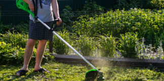 Halbes Foto von einem Mann mit Rasenmäher im Garten.