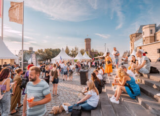 Menschen entspannen auf einem Marktplatz und essen einen Snack.