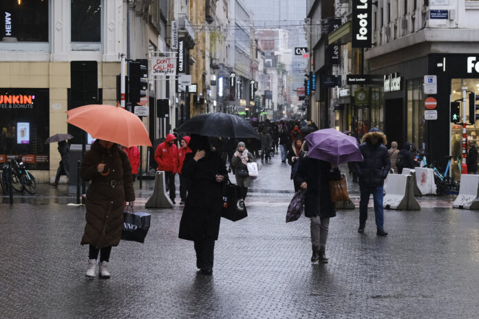 Menschen mit Regenschirmen auf einer verregneten Straße.