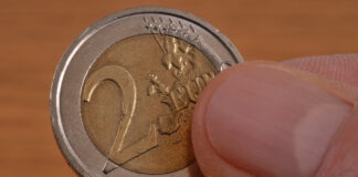 Eine 2-Euro-Münze wird in der Hand gehalten.