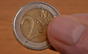 Eine 2-Euro-Münze wird in der Hand gehalten.