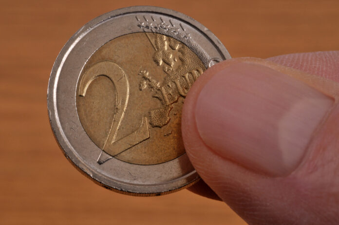 Eine 2-Euro-Münze wird in der Hand gehalten.