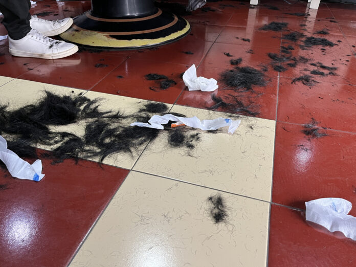 Boden eines Friseursalons mit viel abgeschnittenem Haar und Papiertüchern.