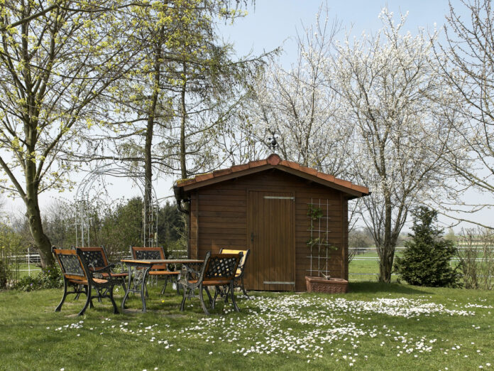 Ein Holzhaus in sommerlicher Ruhe mit Sitzplatz vor der Tür
